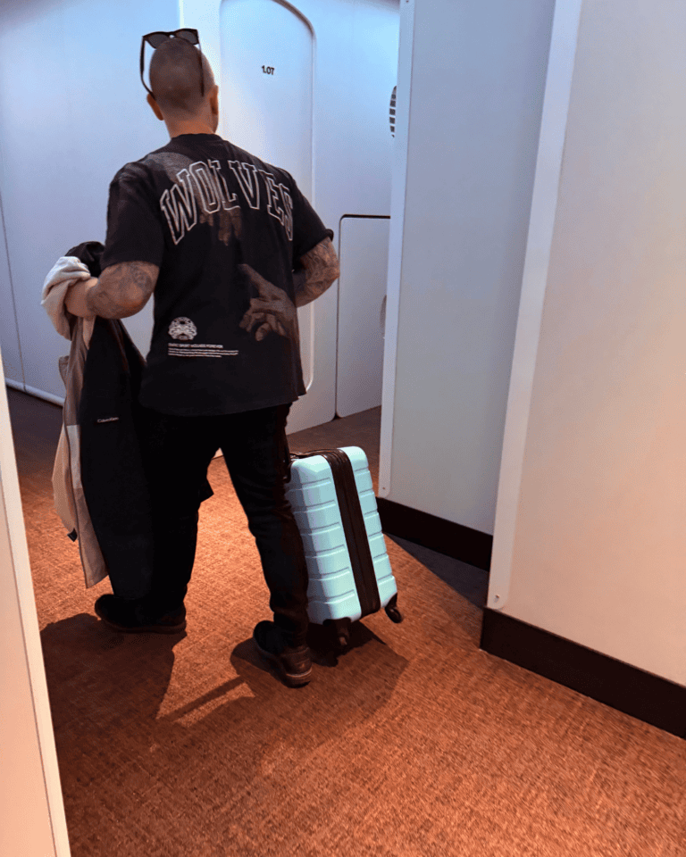 Man pulling a hard-shell carry-on suitcase down a hotel hallway, one of the essential travel abroad must-haves.