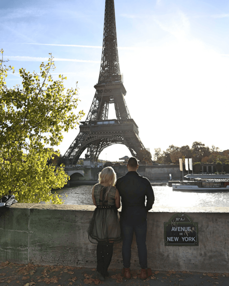 Couple looking out at the Eiffel Tower in Paris, arriving rested after a long international flight.