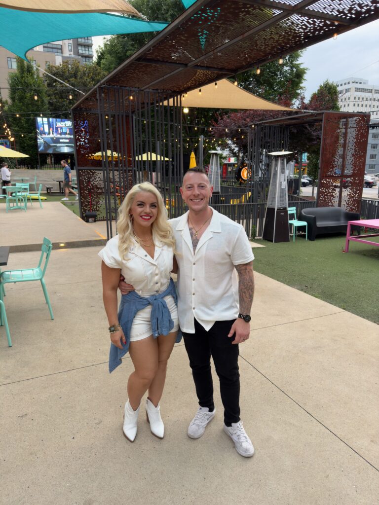 Millennial couple in matching white outfits at an outdoor patio bar in Nashville, a fun date night spot for couples.