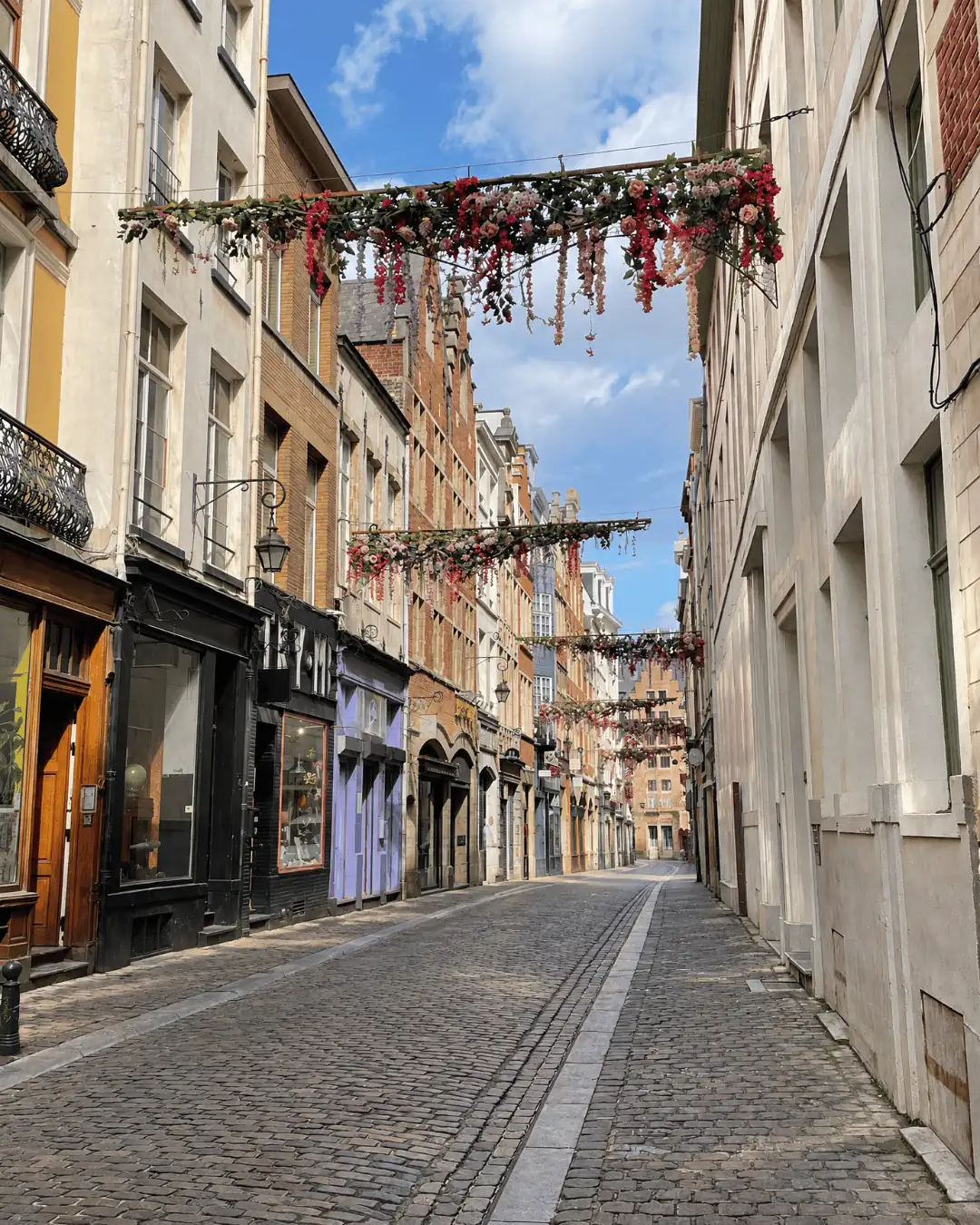 Cobblestone side street in Brussels with flower garlands hanging between the buildings